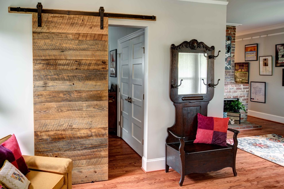 Kleines, Offenes Klassisches Wohnzimmer mit grauer Wandfarbe, braunem Holzboden, Kamin, Kaminumrandung aus Backstein, TV-Wand und braunem Boden in Raleigh