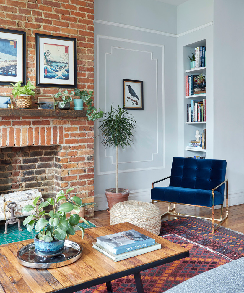 This is an example of a medium sized bohemian living room in New York with grey walls, a standard fireplace and a brick fireplace surround.