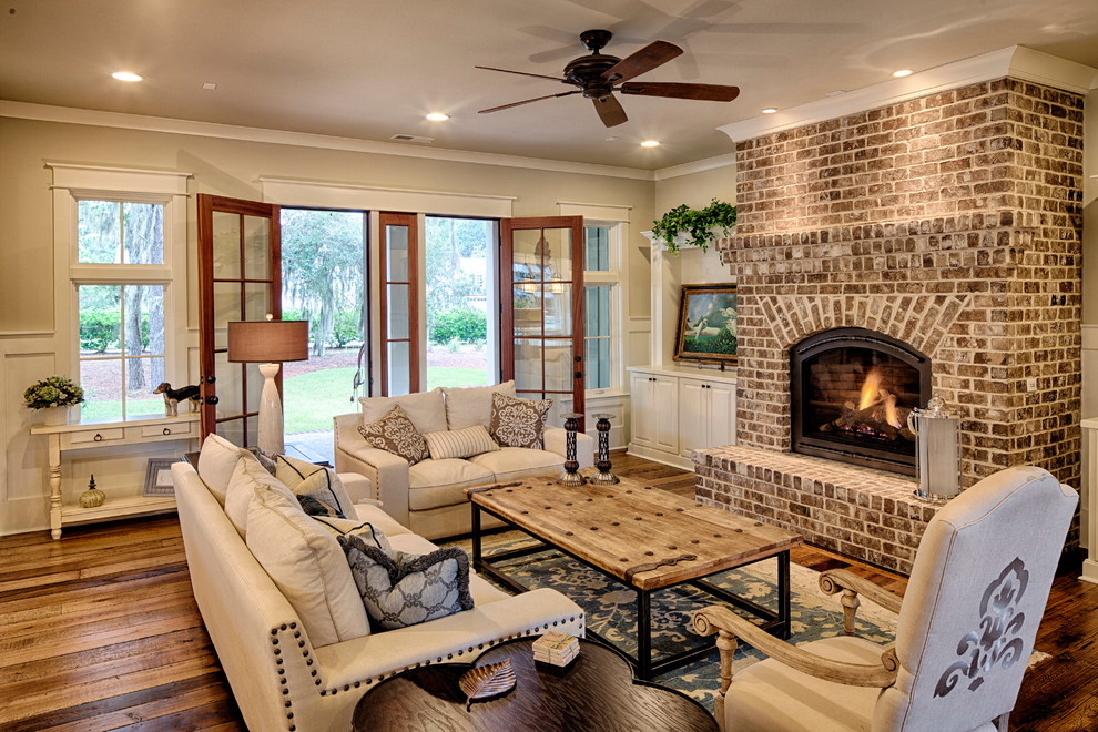 Mid-sized elegant open concept medium tone wood floor living room photo in Charleston with beige walls, a standard fireplace, a brick fireplace and no tv