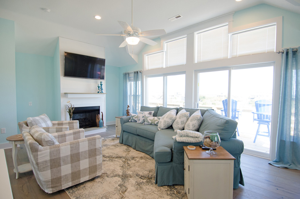 Esempio di un soggiorno stile marinaro chiuso con pareti blu, pavimento in legno massello medio, camino classico, TV a parete e pavimento marrone
