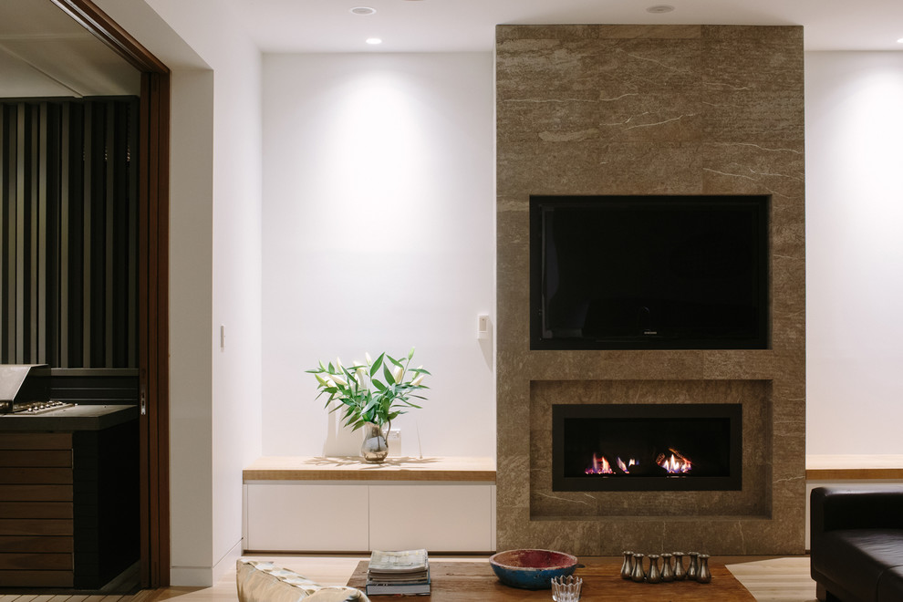 Cette image montre un salon design de taille moyenne et ouvert avec un mur blanc, une cheminée ribbon, un manteau de cheminée en pierre et un téléviseur fixé au mur.
