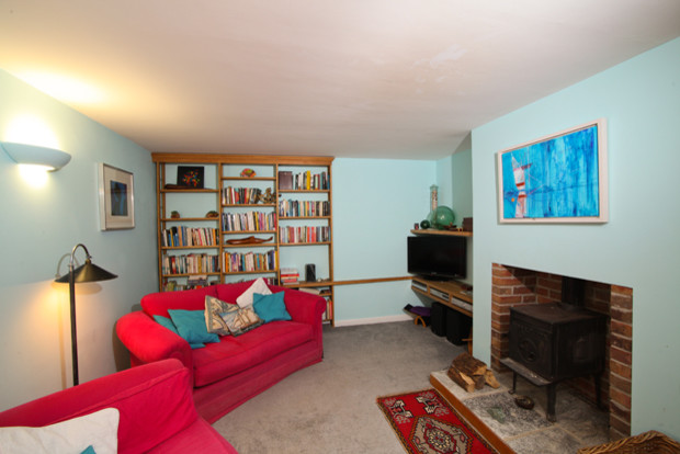 Cette image montre un salon rustique de taille moyenne et fermé avec une bibliothèque ou un coin lecture, un mur bleu, moquette, une cheminée standard, un manteau de cheminée en brique et un téléviseur indépendant.