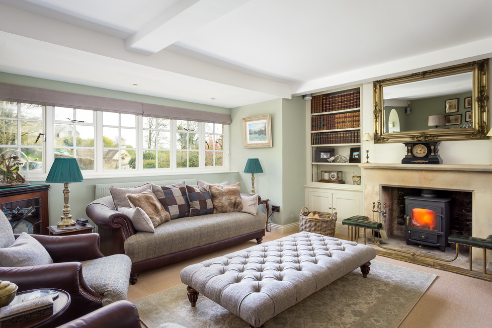 This is an example of a medium sized traditional formal open plan living room in Gloucestershire with green walls, carpet, a wood burning stove, a stone fireplace surround and feature lighting.
