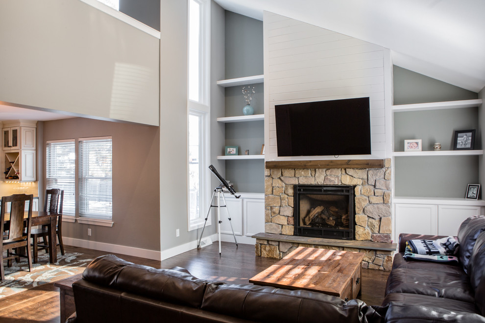 デンバーにある高級な広いトラディショナルスタイルのおしゃれなLDK (ライブラリー、緑の壁、無垢フローリング、標準型暖炉、石材の暖炉まわり、壁掛け型テレビ、茶色い床) の写真