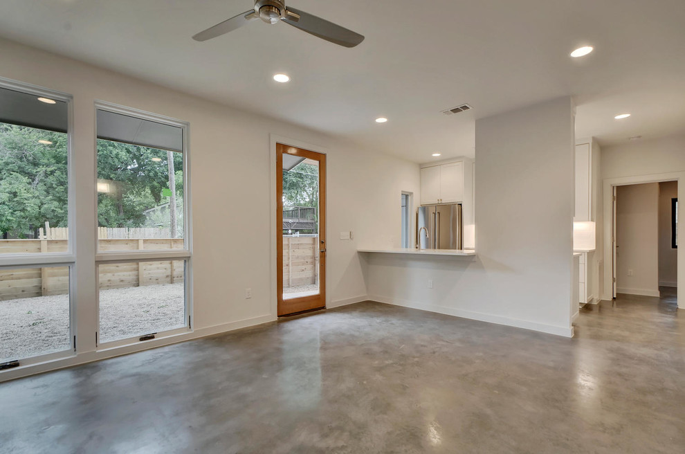This is an example of a small modern living room in Austin with white walls, concrete flooring and grey floors.