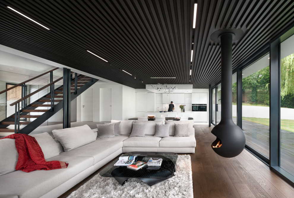 Esempio di un soggiorno minimalista aperto con pareti bianche, parquet scuro, camino sospeso e pavimento marrone