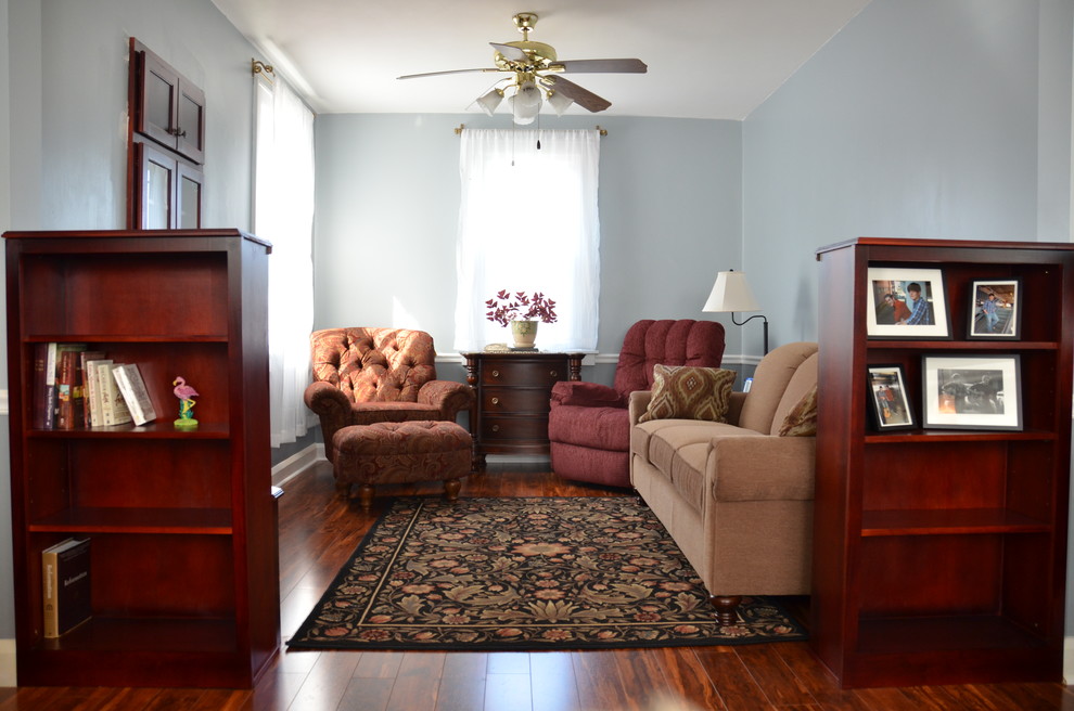 Foto di un piccolo soggiorno classico aperto con sala formale, pareti blu, pavimento in laminato, parete attrezzata, pavimento marrone e nessun camino