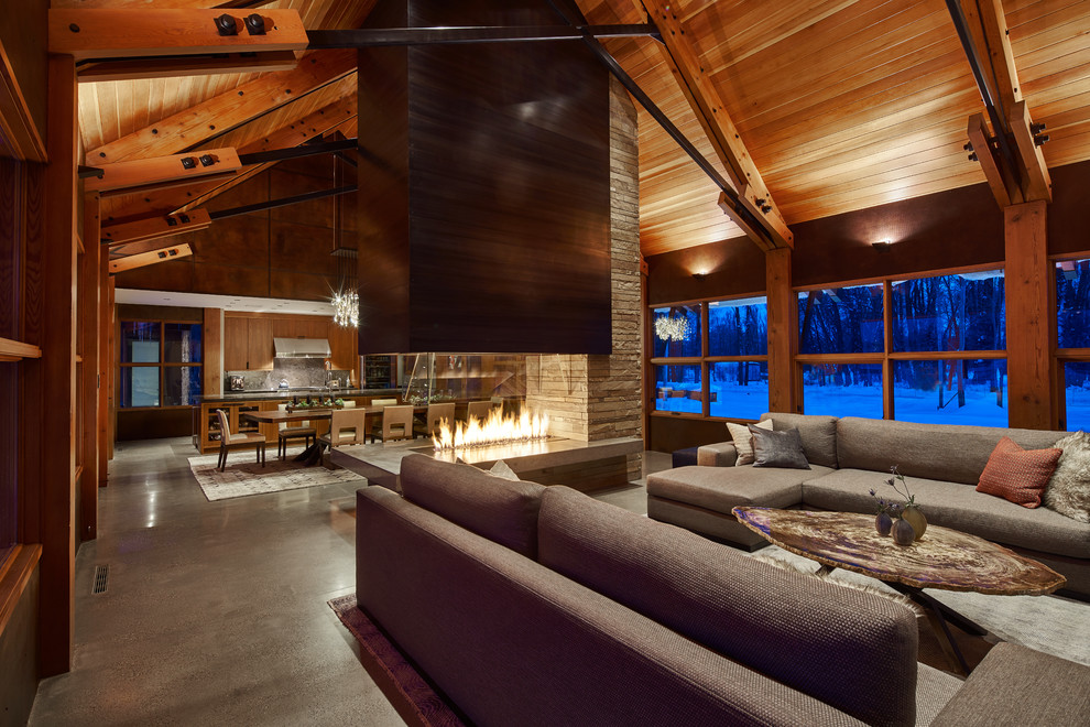 Huge trendy open concept concrete floor living room photo in Portland with a two-sided fireplace