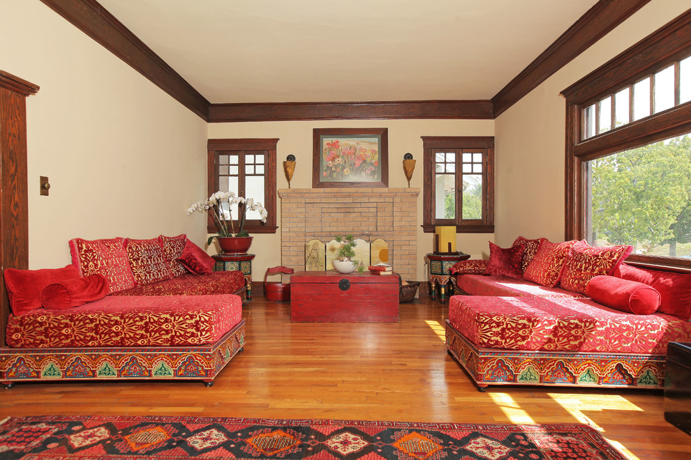 Esempio di un soggiorno stile americano di medie dimensioni e aperto con pareti beige, parquet chiaro, camino classico e cornice del camino in mattoni