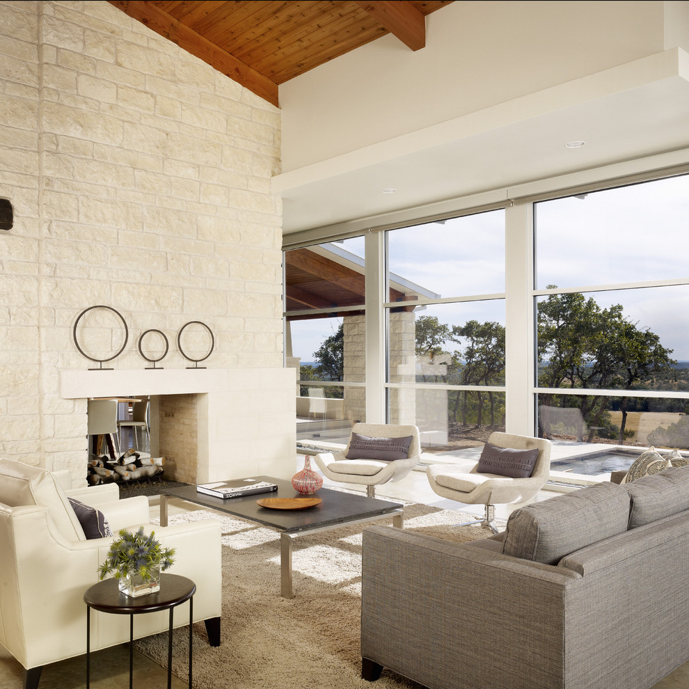 Large modern open plan living room in Austin with beige walls, a two-sided fireplace and a stone fireplace surround.