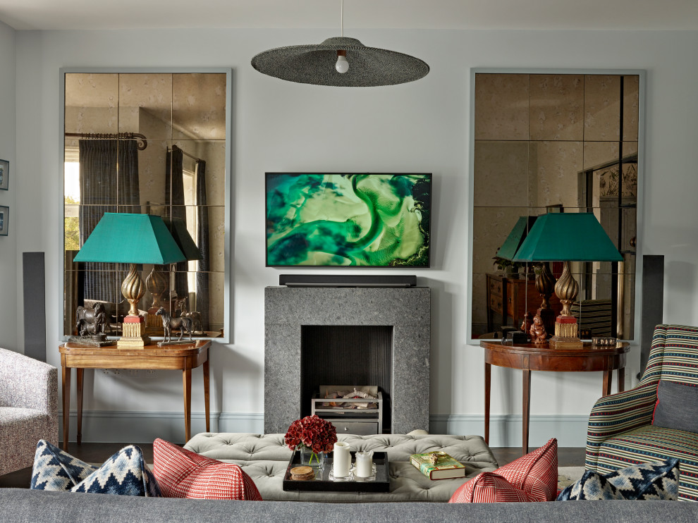 На фото: гостиная комната в стиле фьюжн с белыми стенами, темным паркетным полом, стандартным камином, телевизором на стене и коричневым полом