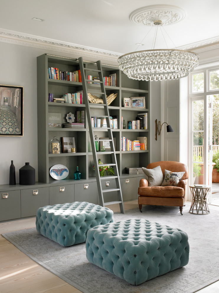 Exemple d'un grand salon chic ouvert avec une bibliothèque ou un coin lecture, un mur gris, parquet clair, une cheminée standard, un manteau de cheminée en pierre, un sol beige et éclairage.