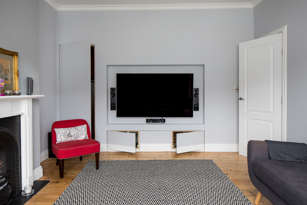 Cette photo montre un salon tendance de taille moyenne et fermé avec un mur gris, une cheminée standard, un téléviseur fixé au mur, un sol marron, une salle de réception, un sol en bois brun et un manteau de cheminée en plâtre.