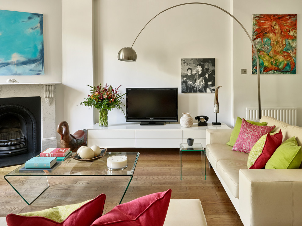 Пример оригинального дизайна: открытая гостиная комната в стиле неоклассика (современная классика) с белыми стенами, паркетным полом среднего тона, стандартным камином, фасадом камина из камня, отдельно стоящим телевизором и коричневым полом