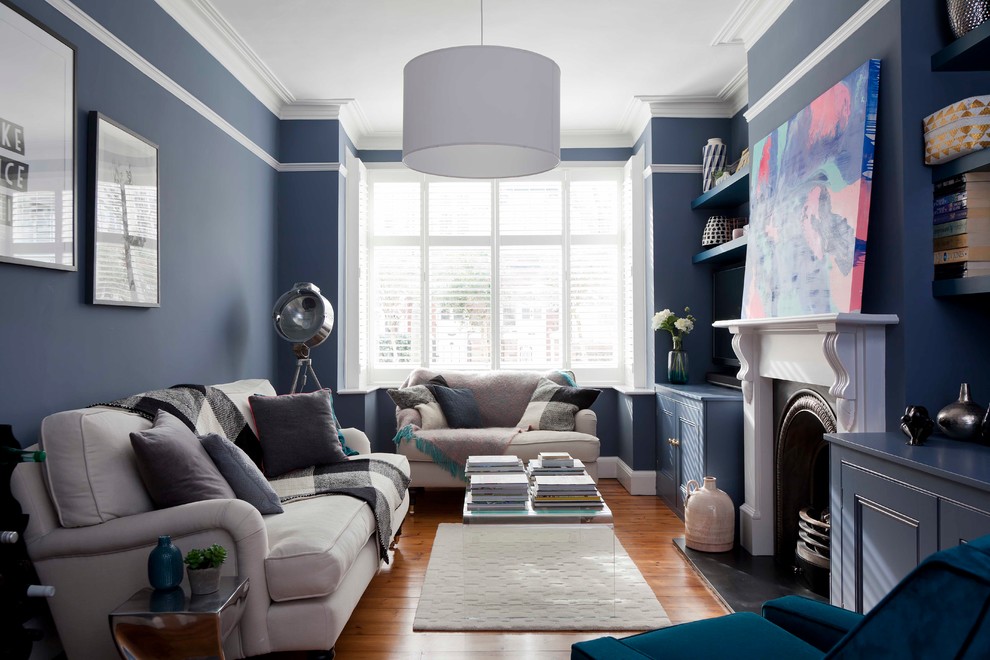 Klassisk inredning av ett mellanstort separat vardagsrum, med blå väggar, mellanmörkt trägolv, en standard öppen spis, en spiselkrans i trä och brunt golv