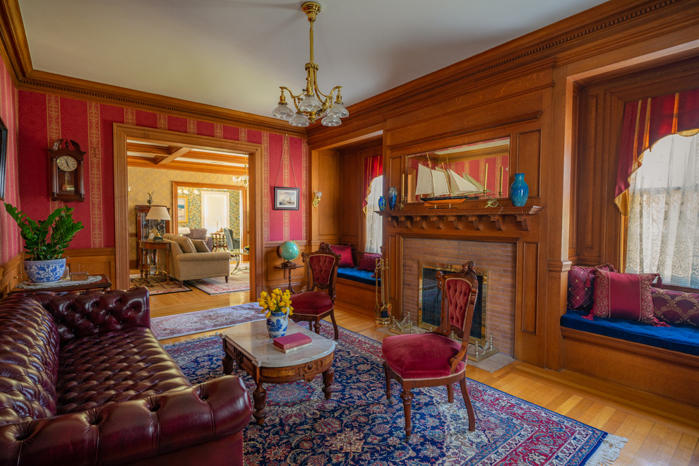 Klassisches Wohnzimmer mit roter Wandfarbe, braunem Holzboden, Kamin, gefliester Kaminumrandung und braunem Boden in Boston