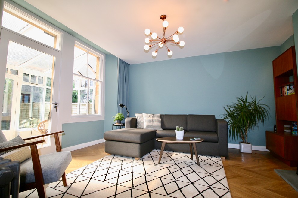 Foto di un grande soggiorno minimalista chiuso con sala formale, pareti blu, pavimento in laminato, cornice del camino in metallo, TV autoportante e pavimento beige