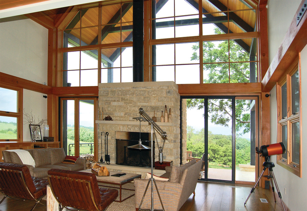 Cette photo montre un grand salon nature ouvert avec un mur marron, un sol en bois brun, une cheminée standard, un manteau de cheminée en brique, une salle de réception et aucun téléviseur.