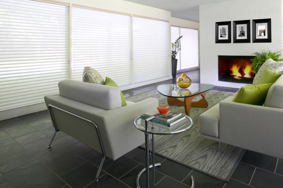 Пример оригинального дизайна: парадная, изолированная гостиная комната среднего размера в современном стиле с белыми стенами, полом из сланца, стандартным камином, фасадом камина из кирпича и черным полом без телевизора