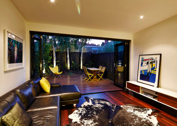 Réalisation d'un petit salon design ouvert avec un mur blanc, un sol en bois brun et un téléviseur fixé au mur.