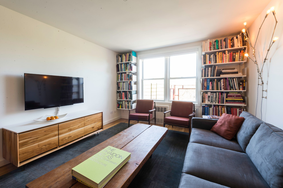 Foto di un soggiorno moderno di medie dimensioni e chiuso con libreria, pareti bianche, pavimento in legno massello medio, nessun camino e TV a parete
