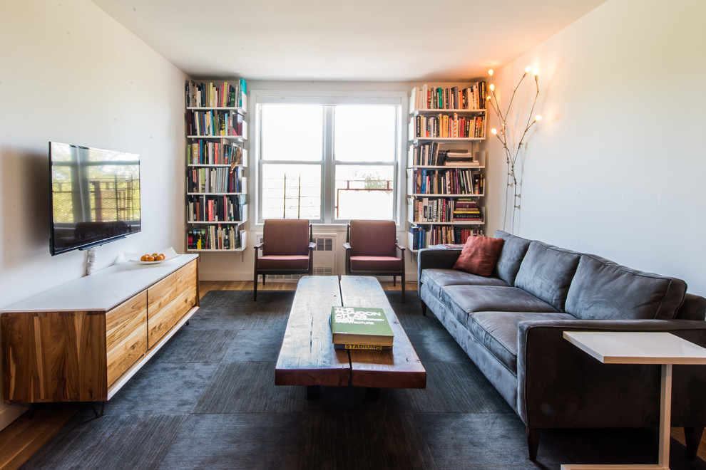 Esempio di un soggiorno design di medie dimensioni e chiuso con pareti bianche, pavimento in legno massello medio, TV a parete, libreria e nessun camino