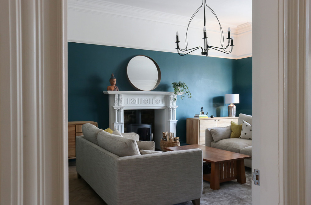 Пример оригинального дизайна: большая изолированная гостиная комната в стиле фьюжн с с книжными шкафами и полками, синими стенами, полом из винила, печью-буржуйкой, фасадом камина из дерева и коричневым полом без телевизора