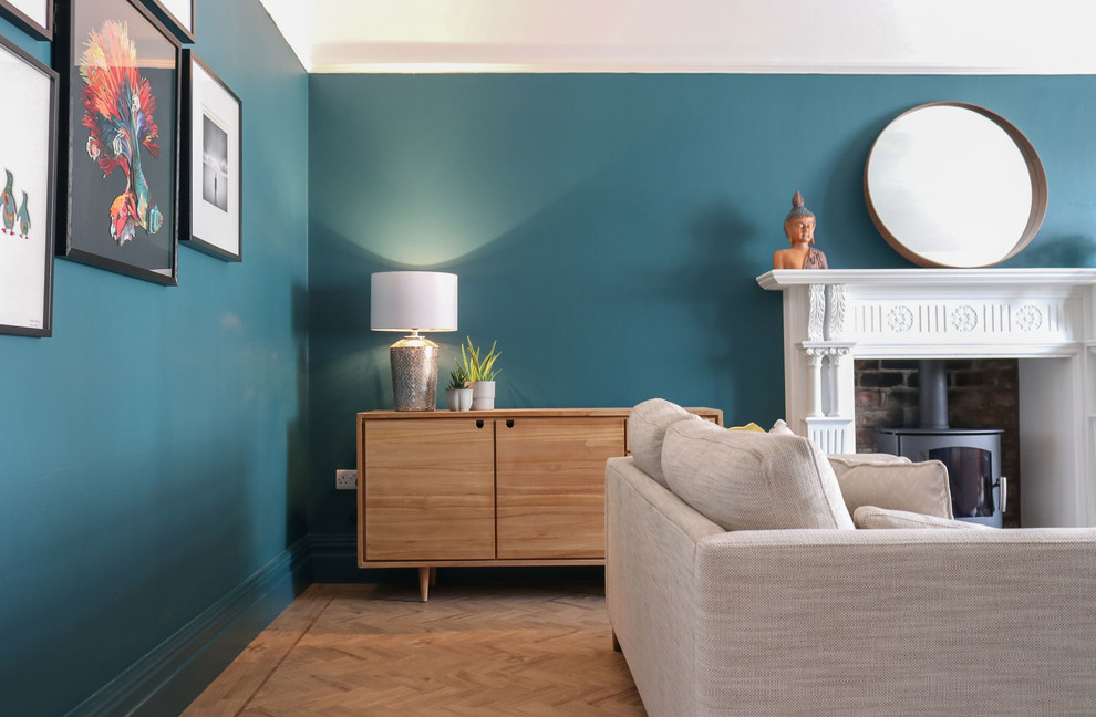 Пример оригинального дизайна: большая изолированная гостиная комната в стиле фьюжн с с книжными шкафами и полками, синими стенами, полом из винила, печью-буржуйкой, фасадом камина из дерева и коричневым полом без телевизора