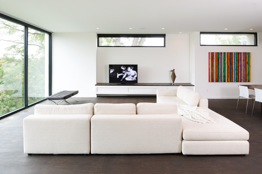 Стильный дизайн: открытая гостиная комната в стиле модернизм с белыми стенами и отдельно стоящим телевизором - последний тренд