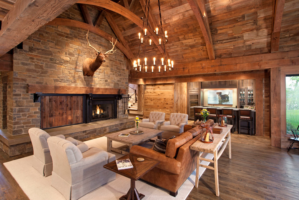 Imagen de salón para visitas abierto rústico con suelo de madera en tonos medios, todas las chimeneas y marco de chimenea de piedra