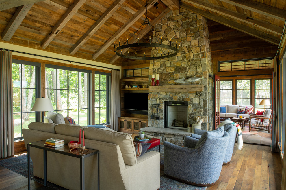 Cette image montre un salon chalet fermé avec un mur marron, parquet foncé, une cheminée standard, un manteau de cheminée en pierre, un téléviseur fixé au mur et un sol marron.