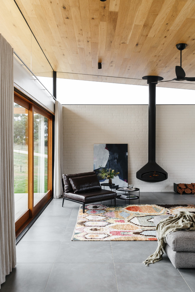 Idee per un soggiorno minimal con pareti bianche, pavimento in cemento, camino sospeso e pavimento grigio