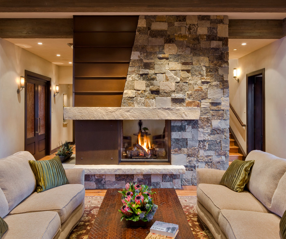 Rustic formal living room in Denver with beige walls, medium hardwood flooring, a two-sided fireplace, a stone fireplace surround and no tv.