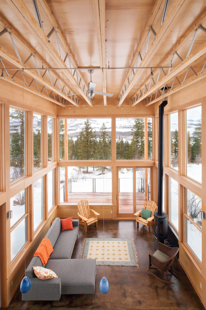 Ispirazione per un grande soggiorno minimalista stile loft con pavimento in cemento, stufa a legna, cornice del camino in metallo e nessuna TV