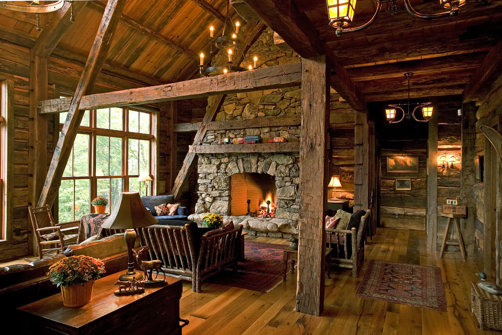 Ejemplo de salón rural con paredes marrones, suelo de madera en tonos medios, todas las chimeneas y marco de chimenea de piedra