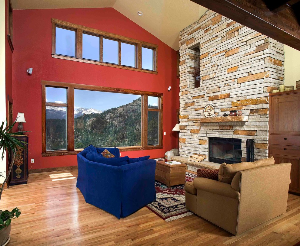 Свежая идея для дизайна: открытая гостиная комната среднего размера в стиле рустика с красными стенами, паркетным полом среднего тона, стандартным камином и фасадом камина из камня - отличное фото интерьера