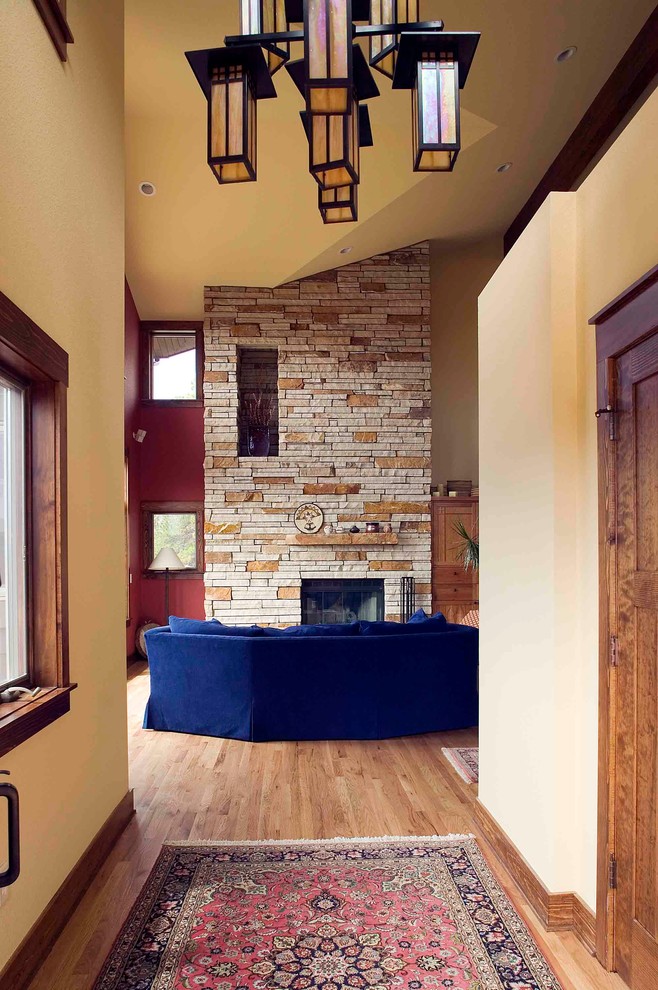 Идея дизайна: открытая гостиная комната среднего размера в стиле рустика с красными стенами, паркетным полом среднего тона, стандартным камином и фасадом камина из камня