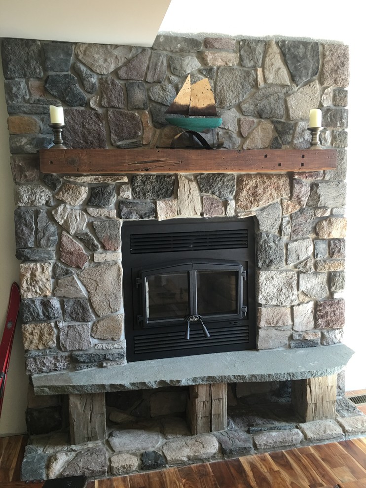 Imagen de salón rural de tamaño medio con estufa de leña y marco de chimenea de piedra