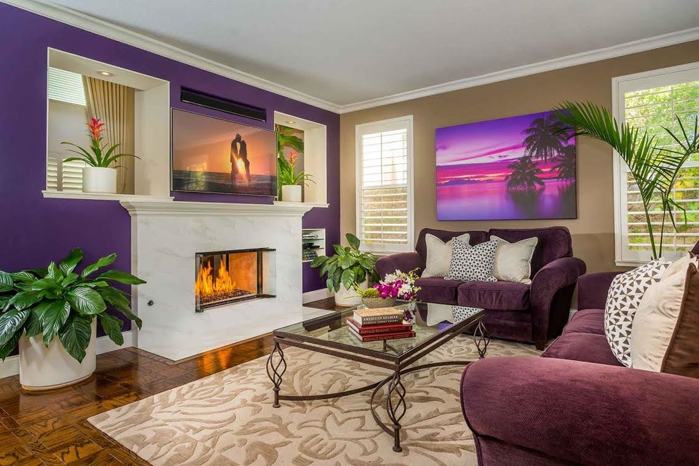Exemple d'un salon exotique de taille moyenne et fermé avec un mur violet, un sol en bois brun, une cheminée ribbon, un manteau de cheminée en carrelage et un téléviseur fixé au mur.