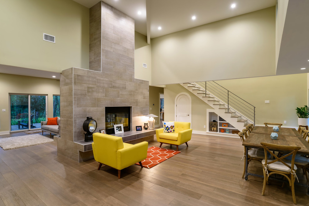 Offenes Modernes Wohnzimmer mit grüner Wandfarbe, braunem Holzboden, Kamin, gefliester Kaminumrandung und braunem Boden in Jacksonville