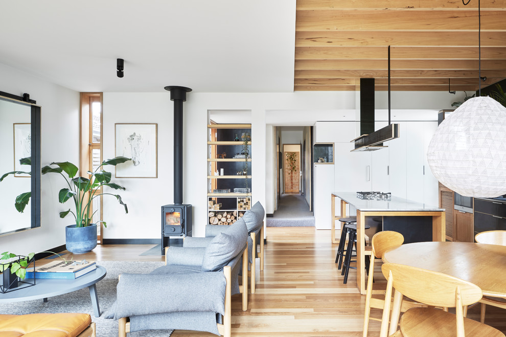 Idee per un piccolo soggiorno contemporaneo aperto con pareti bianche, parquet chiaro, stufa a legna e TV nascosta