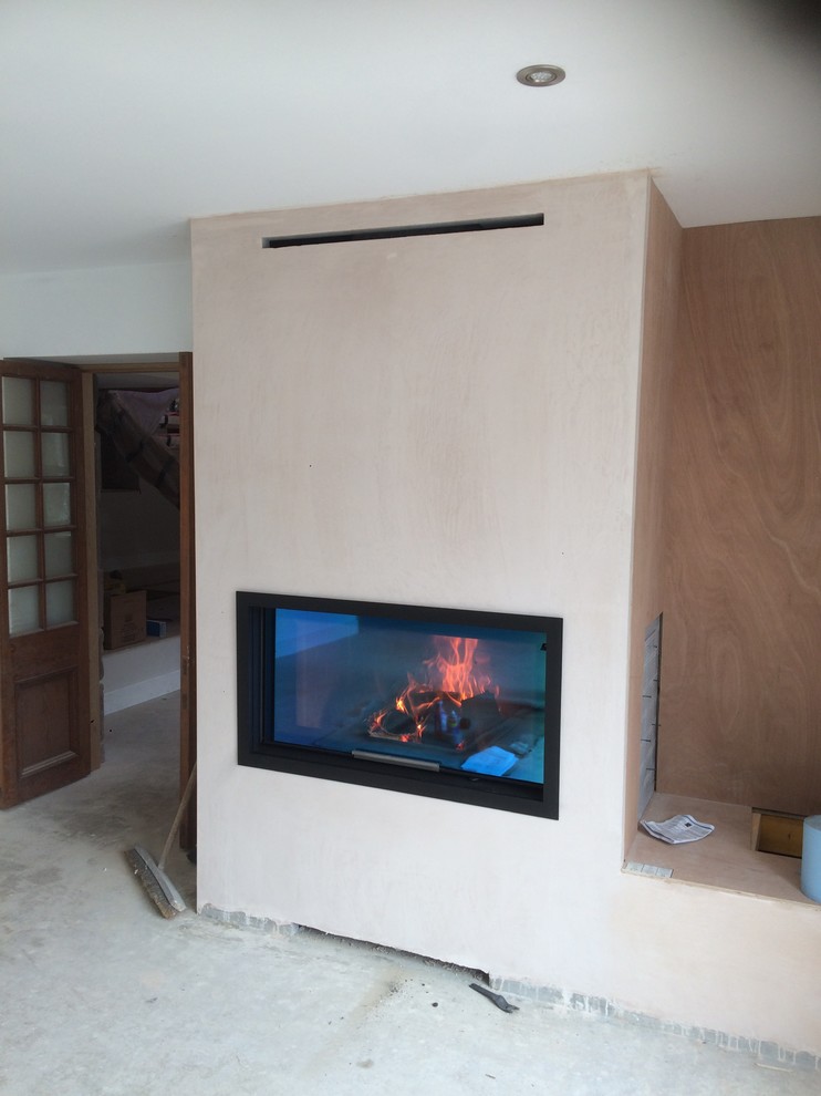 This is an example of a contemporary living room in Other with a wood burning stove and a plastered fireplace surround.