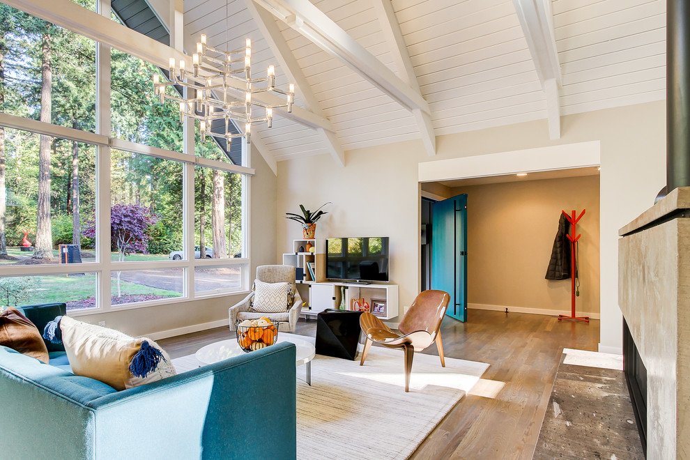 Diseño de salón abierto contemporáneo grande con paredes beige, suelo de madera en tonos medios, chimenea de doble cara, marco de chimenea de yeso y televisor independiente