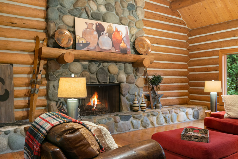 Idée de décoration pour un très grand salon chalet en bois ouvert avec un sol en bois brun, une cheminée standard, un manteau de cheminée en pierre et un plafond en bois.