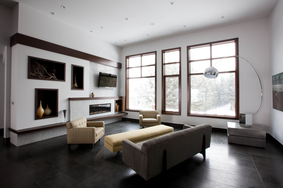 Exempel på ett mellanstort modernt allrum med öppen planlösning, med vita väggar, skiffergolv, en bred öppen spis, en spiselkrans i trä, en väggmonterad TV och svart golv