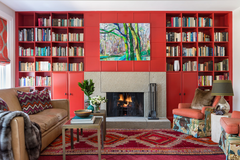 Cette photo montre un grand salon chic ouvert avec une bibliothèque ou un coin lecture, un mur rouge, une cheminée standard, parquet clair, un manteau de cheminée en béton et aucun téléviseur.