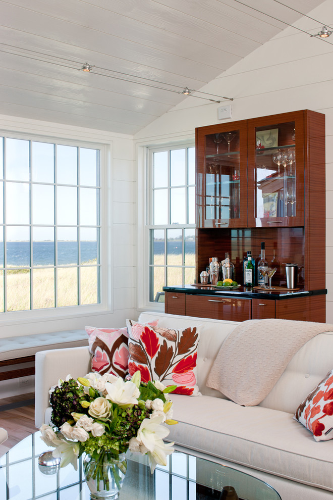Modelo de salón con barra de bar abierto costero pequeño con paredes blancas y suelo de madera clara