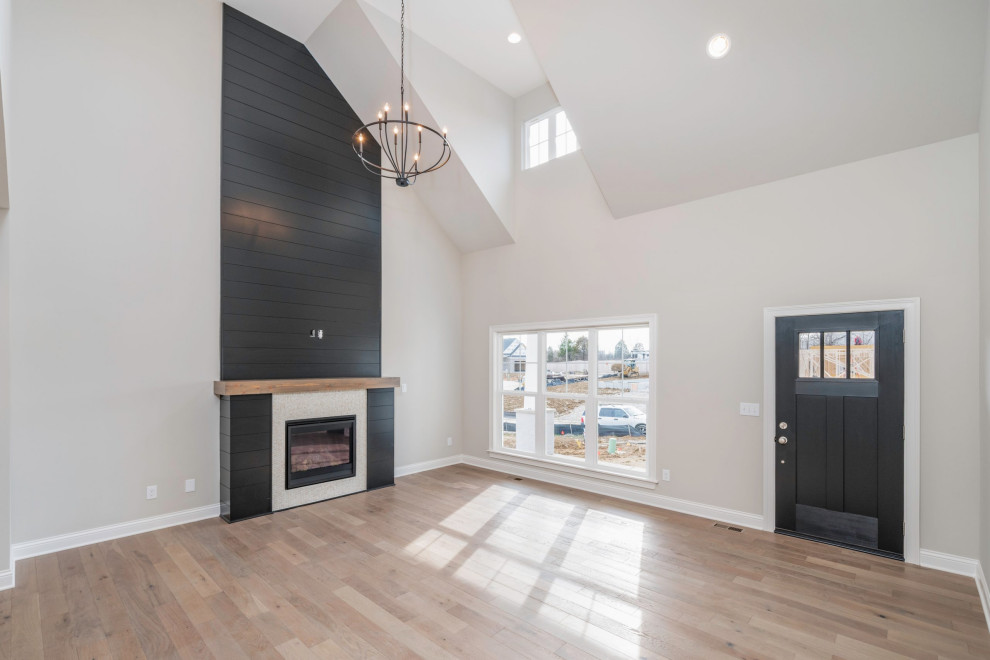 Inspiration for an industrial open concept ceramic tile, black floor, vaulted ceiling and shiplap wall living room remodel in Huntington with beige walls, a standard fireplace and a tile fireplace