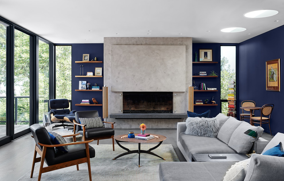 Пример оригинального дизайна: гостиная комната в стиле ретро с с книжными шкафами и полками, синими стенами, горизонтальным камином, фасадом камина из бетона и ковром на полу без телевизора