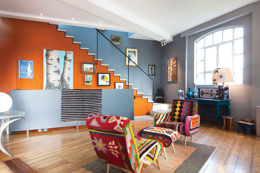 Exemple d'un salon éclectique ouvert avec une salle de réception, un mur multicolore, un sol en bois brun et un escalier.